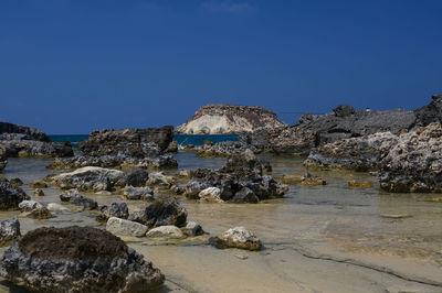 Rocks on beach against clear blue sky