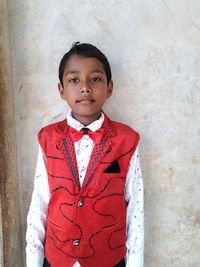 Portrait of cute boy standing against wall