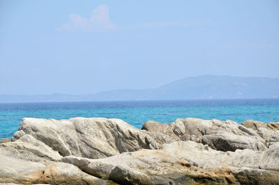 Sea rocks and turquoise sea water with land in distance