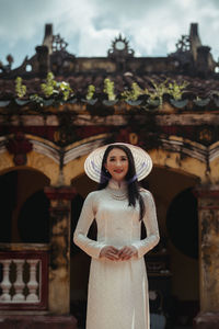 Portrait of woman standing against built structure