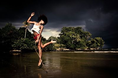 Silhouette of woman jumping on tree trunk