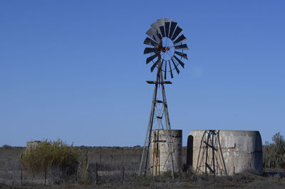 Low angle view of traditional windmill on field against clear sky