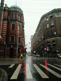 Wet street amidst buildings in city during rainy season