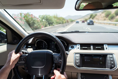 Crop man driving modern car on sunny day in countryside