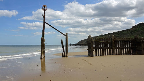 Wooden posts on beach against sky