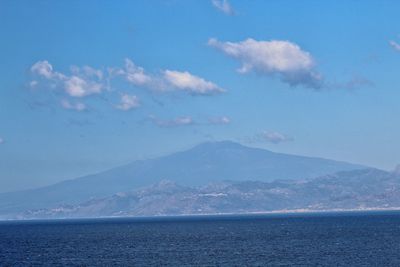 Scenic view of sea by mountains against sky