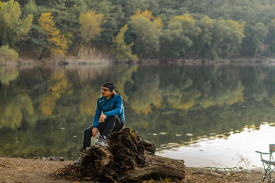 Man sitting on rock by lake