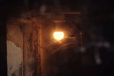 Close-up of illuminated light bulb against wall