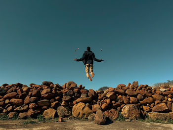 Young man levitating over rock wall
