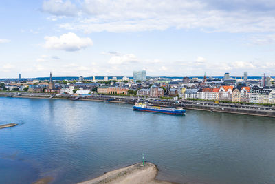 Bridge over river by buildings in city against sky