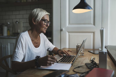 Mature female designer working late at home office