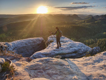 Photographer is setting tripod and camera for an art work. takes camera on tripod on rocky peak