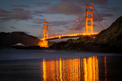 Low angle view of illuminated golden gate bridge over sea during sunset