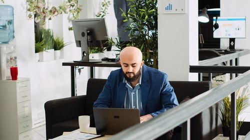 Young woman using laptop while sitting on table