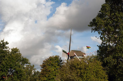 Low angle view of flag amidst trees and building against sky