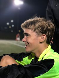 Side view of young athlete looking away at illuminated stadium