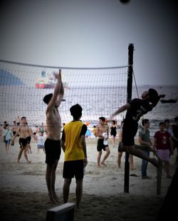 Group of people playing soccer against sky