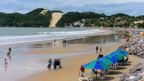 People at beach against mountains