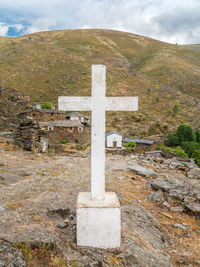 Cross in cemetery against sky