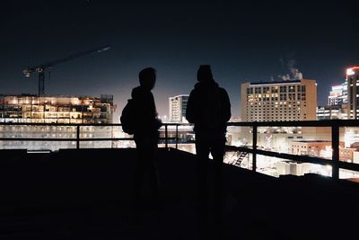 Rear view of men on city at night
