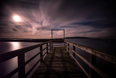 Empty pier over sea against sky during sunset