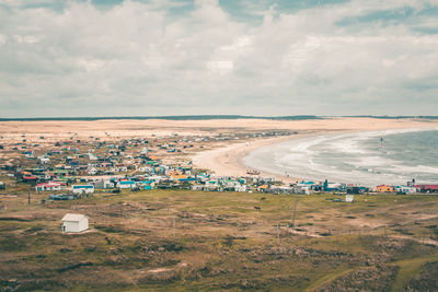 Scenic view of village by sea against sky