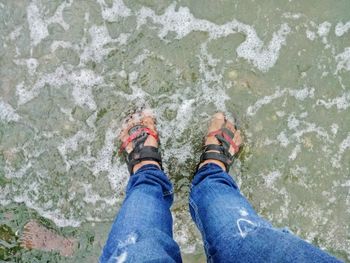 Low section of people standing in sea