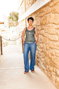 Portrait of smiling woman standing against brick wall