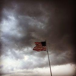 Low angle view of american flag against cloudy sky