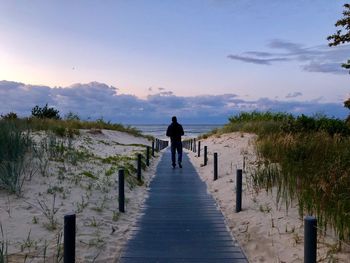 Rear view of man standing on footpath against sky