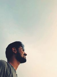 Portrait of young man looking away against sky