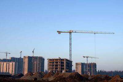 Cranes at construction site against sky