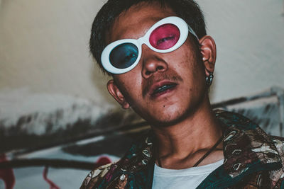 Portrait of young man wearing sunglasses at home