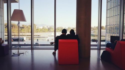 People sitting on chair seen through window