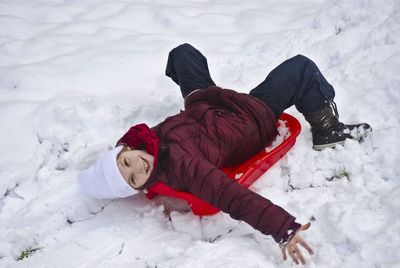High angle view of child lying down on snow field
