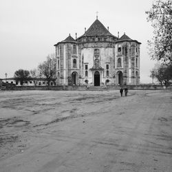Man walking by building against clear sky