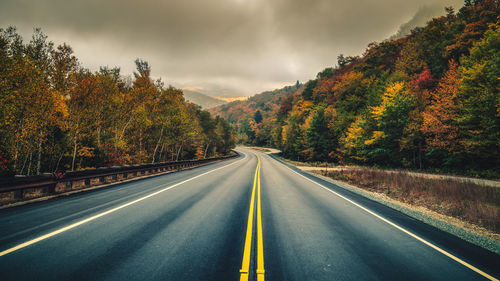 Road amidst trees against sky during autumn