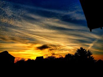 Silhouette of trees against dramatic sky during sunset