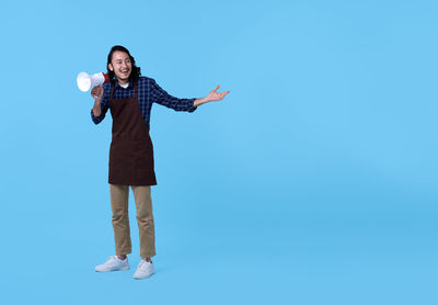 Portrait of smiling young woman against blue background