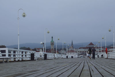 Street by pier against sky in city