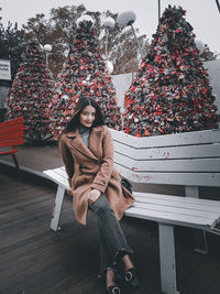 Portrait of woman sitting on bench in winter