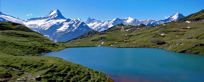 Scenic view of lake and mountains against blue sky