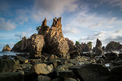 Rock formations on beach against sky