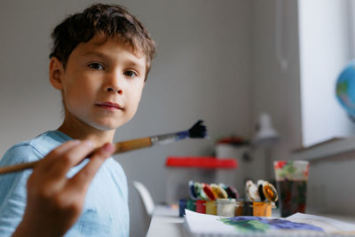 Portrait of boy painting at home