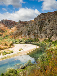 Scenic view of lake by mountains against sky