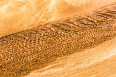 Full frame shot of water flowing through sand.