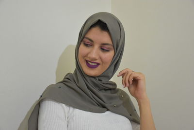 Portrait of smiling young woman against wall