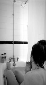 Rear view of woman sitting in bathroom