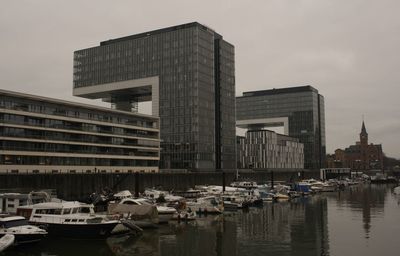 Boats moored in harbor against buildings in city