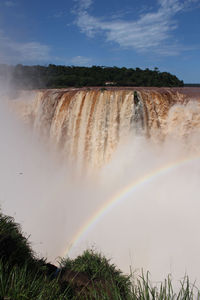 Scenic view of waterfall against sky